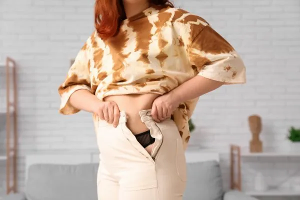 Image of woman trying to do her trousers up after pregnancy weight gain Tamworth